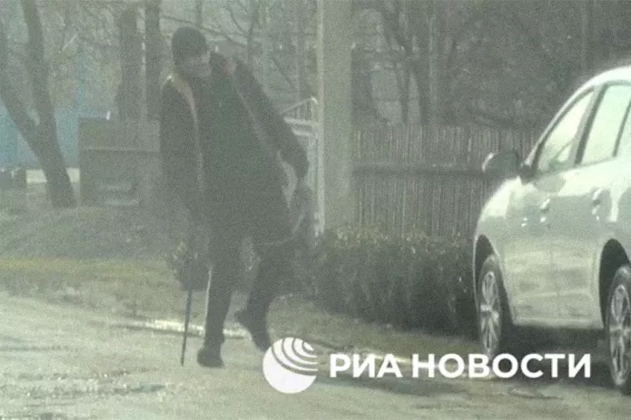 A screenshot of a video published by the FSB showing a man with a cane placing a package under a car