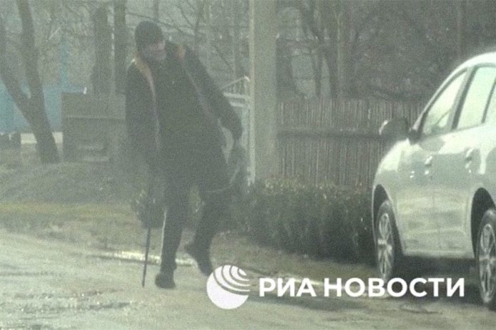 A screenshot of a video published by the FSB showing a man with a cane placing a package under a car