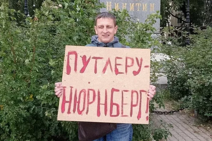 <em>Григорий Северин в одиночном пикете. За этот же плакат в январе 2021 года его <a href="https://mekodxpr-bsccljbcrq-ez.a.run.app/express-news/2021/01/20/voronezhca-arestovali-iz-za-odinochnogo-piketa-v-podderzhku-navalnogo"><u>арестовали</u></a> на пять суток (ч. 8 ст. 20.2 КоАП РФ) / Фото: Свободные Люди Воронежа</em>