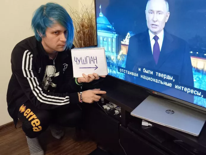 <em>Yury Chilikin holding a poster reading ‘chushpan’ (derogatory slang term, roughly equivalent to ‘patsy’) during Putin’s New Year’s speach / Photo: Yuri Chilikin’s social networks</em>