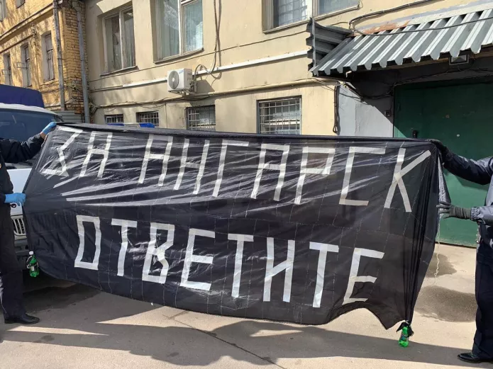 Полицейские держат плакат активистов АНС в поддержку заключенных ИК-15 в Ангарске / Фото: телеграм-канал «Кремлевская прачка»