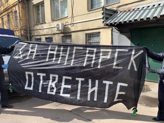 Полицейские держат плакат активистов АНС в поддержку заключенных ИК-15 в Ангарске / Фото: телеграм-канал «Кремлевская прачка»